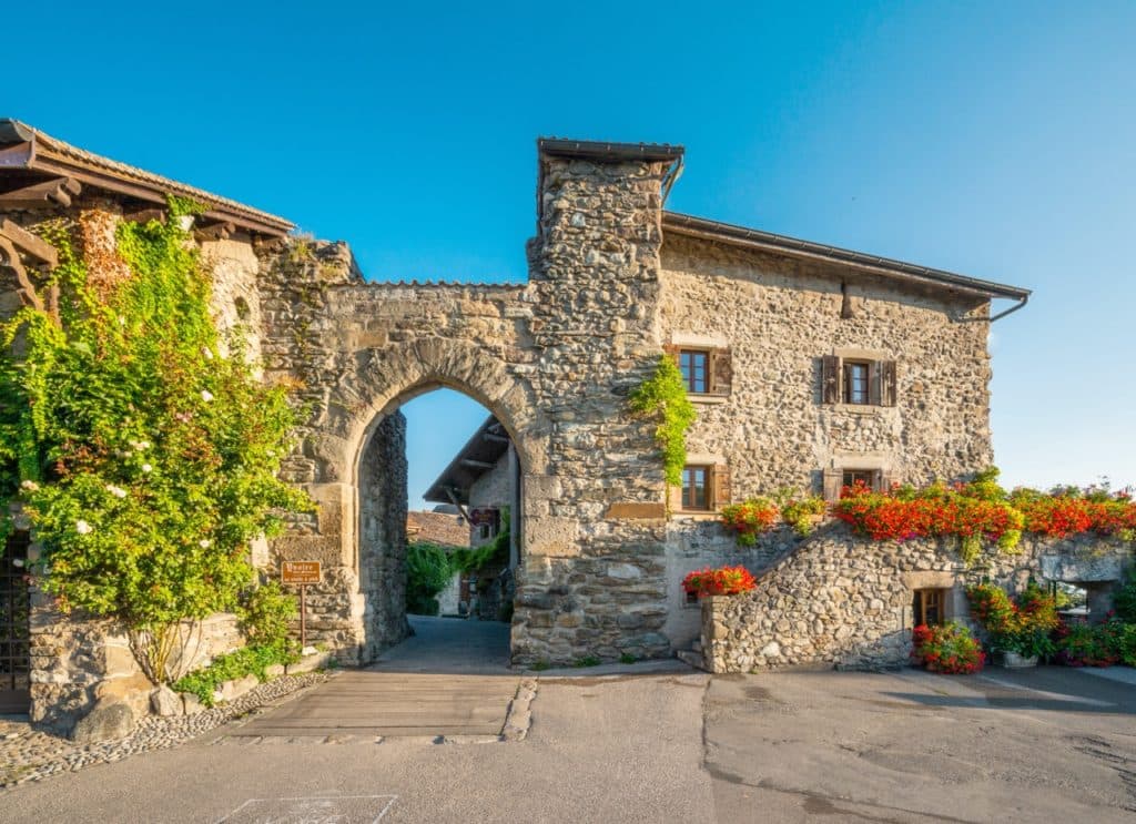 Blumengeschmückte Steinfassaden entlang einer Strasse in Yvoire, Frankreich